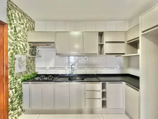 Cozinha moderna com armários brancos e bancadas escuras.