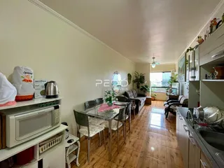Interior de uma sala de estar com piso de madeira e mesa de jantar em Lajeado.