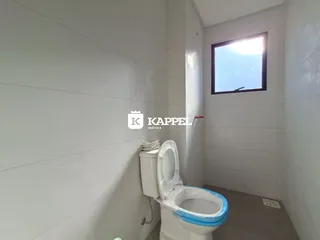 Banheiro com vaso sanitário branco e parede clara.