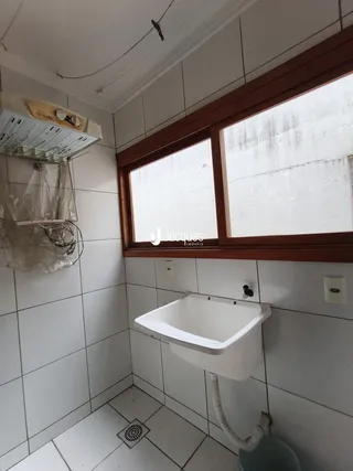 Banheiro com revestimento cerâmico branco e janela de madeira.