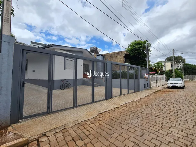 Vista externa de uma propriedade com cerca de metal e pavimento de tijolos.