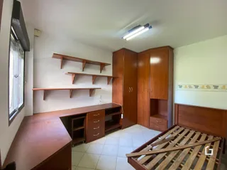 Quarto com cabeceira de madeira e armário no interior de uma residência.