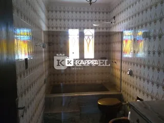 Banheiro com revestimento de azulejos claros e box de vidro.