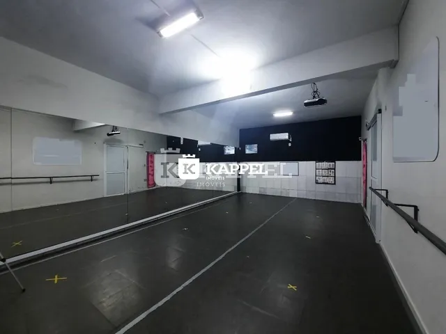 Foto de um espaço interno amplo com piso escuro e paredes brancas.