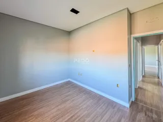 Ambiente interno de uma sala com piso de madeira clara e paredes cinzas.