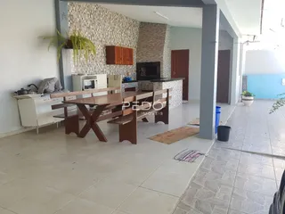 Ambiente interno de sala de jantar e cozinha com parede de destaque em pedra.
