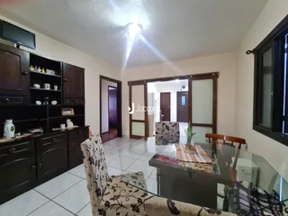 Sala de estar com móveis de madeira escura e piso de cerâmica clara.