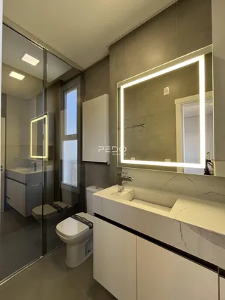 Banheiro moderno com bancada de mármore e espelho iluminado.