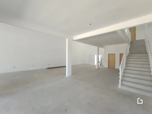 Espaço interno vazio com paredes brancas e escadaria.