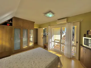 Quarto com armários em madeira e porta de vidro.