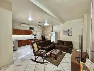 Sala de estar com cozinha integrada e piso de cerâmica em imóvel no Brasil.
