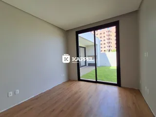 Vista de um cômodo com piso de madeira e porta de vidro que dá acesso a um jardim.