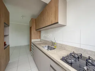 Vista da cozinha com armários de madeira e bancada clara.
