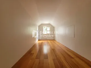Corredor interno com piso de madeira clara.