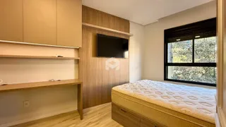 Quarto com cabeceira de madeira e janela com vista para a vegetação externa.