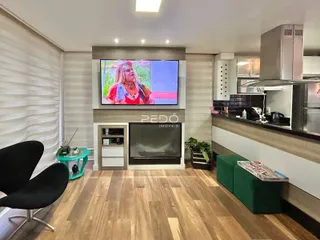 Sala de estar com piso de madeira e área de cozinha visível.