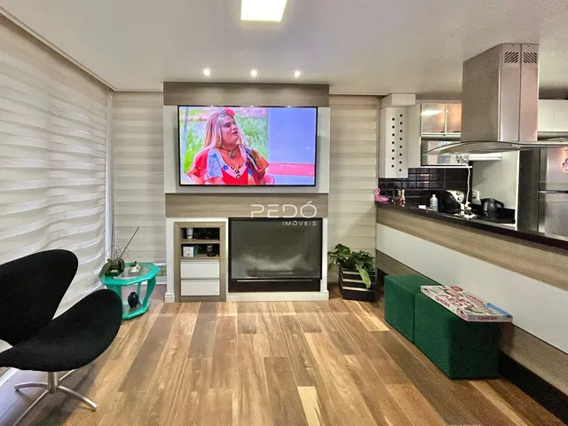 Sala de estar com piso de madeira e área de cozinha visível.