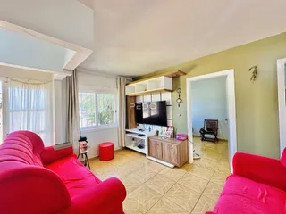 Sala de estar com sofá vermelho e janelas na residência.
