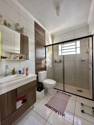 Banheiro moderno com box de vidro e piso de cerâmica clara.