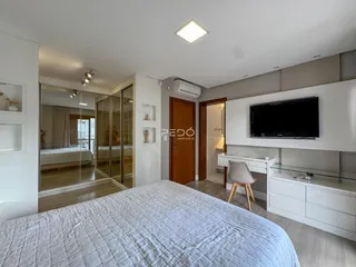 Quarto com cama e espelho refletindo o ambiente interno.