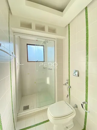 Foto de um banheiro com revestimento de azulejos brancos e verdes.