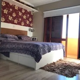 Quarto com cama de casal e cabeceira em parede decorada.
