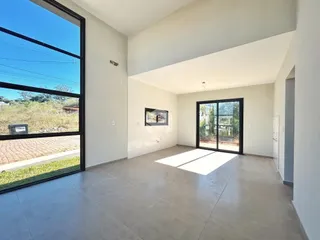 Sala de estar com grandes janelas de vidro e piso de concreto.
