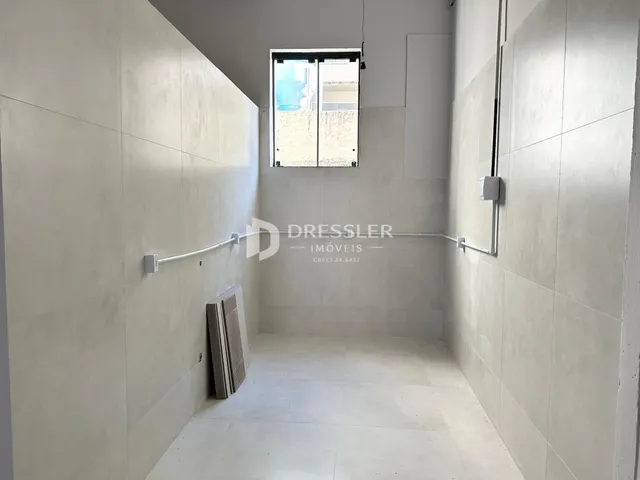 Corredor interno com paredes brancas e piso claro.