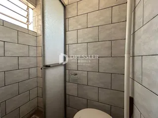 Ambiente interno de um banheiro com revestimento de azulejos claros.