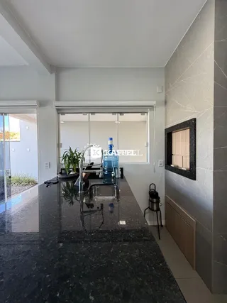 Vista de uma área de cozinha moderna com bancada escura e grande janela.