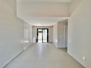 Hall de entrada de uma residência com paredes brancas e piso claro.