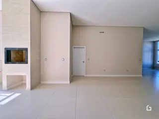 Vista interna de uma sala ampla com paredes claras e piso de cerâmica.