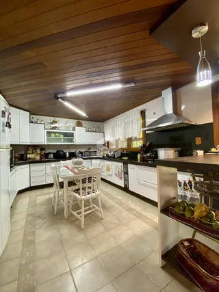 Cozinha e sala de jantar com armários brancos.