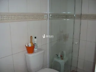 Foto de um banheiro com azulejos brancos e box de vidro.