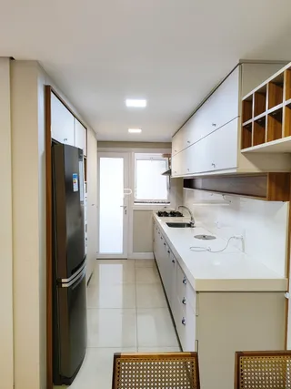 Foto de uma cozinha com armários brancos e piso claro.