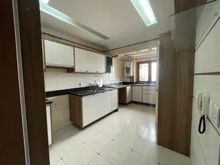 Interior de uma cozinha com armários brancos e piso claro.