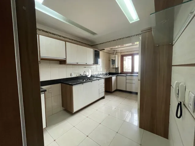 Interior de uma cozinha com armários brancos e piso claro.