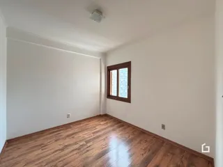 Ambiente interno de uma sala com piso de madeira e janela.