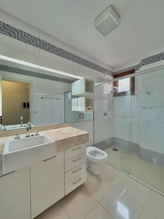 Esta é uma foto de um banheiro moderno com box de vidro e bancada de mármore.