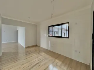 Interior de uma sala com piso de madeira clara e paredes brancas.