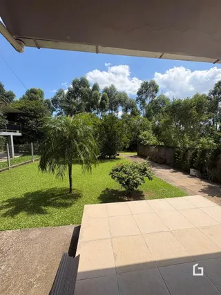 Vista externa do terreno com gramado e vegetação ao fundo.