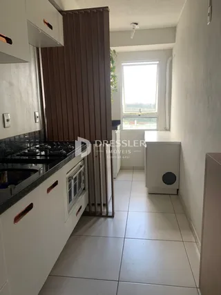 A cozinha de um imóvel em Lajeado, Brasil, com armários brancos e bancada escura.