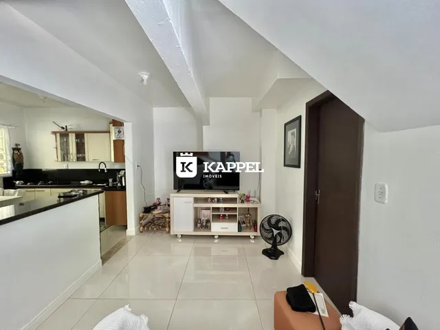 Sala de estar com cozinha aberta e piso de cerâmica.