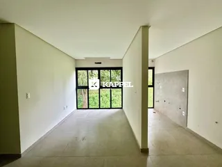 Hall de entrada com paredes brancas e porta de vidro voltada para a vegetação.