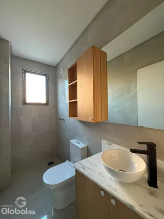 Foto de um banheiro com louças sanitárias e armários de madeira.