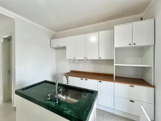 Cozinha moderna com armários brancos e bancada verde.