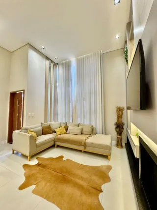 Uma sala de estar clara com sofá e cortinas brancas é visível na propriedade.