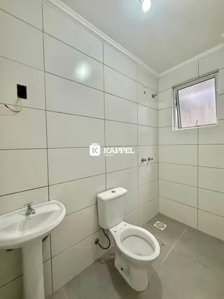 Foto de um banheiro com paredes brancas e louças sanitárias.
