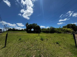 Vista aérea de um campo gramado sob um céu azul com nuvens brancas.