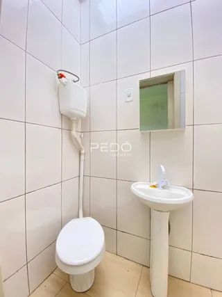 Foto de um banheiro com azulejos brancos e louças sanitárias.